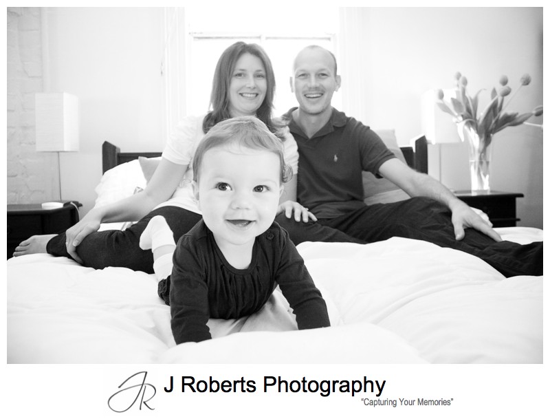 Baby girl with parents on her bed - family portrait photography sydney