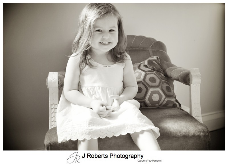 Sepia portrait of 2 year old girl on old fashioned seat - family portrait photography sydney