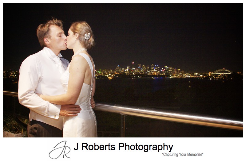 Bride and groom kissing with sydney night sky behind from Taronga Zoo - wedding photography sydney