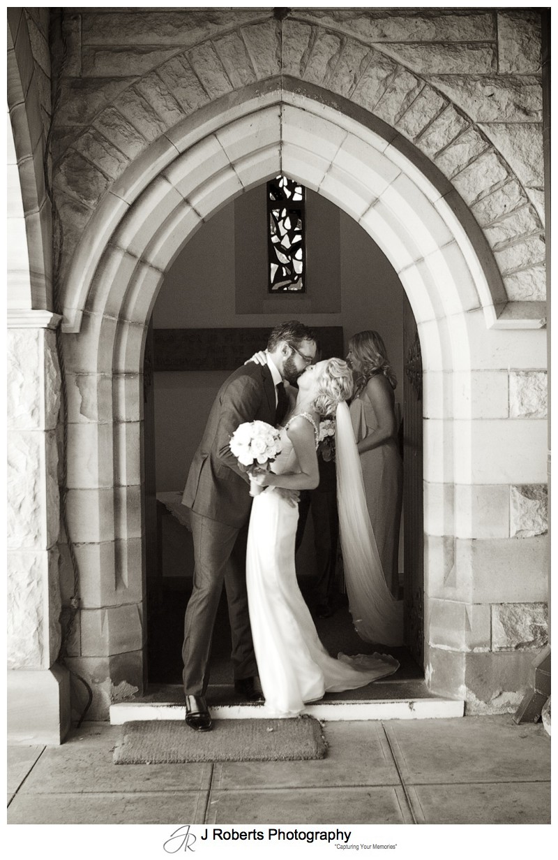 Bride and groom kissing outside St Francis Xavier Church - wedding photography sydney