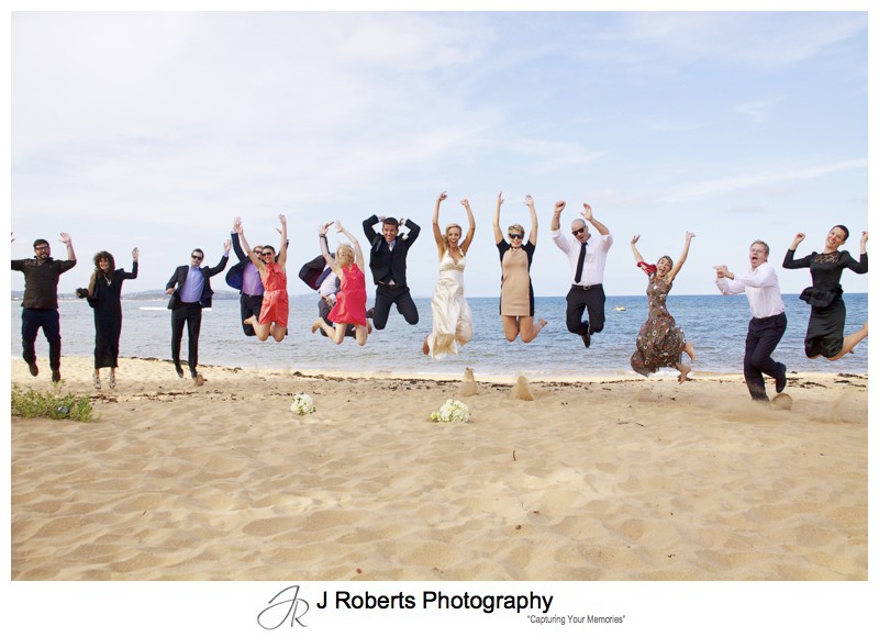 Couple and friends jumping on Long Reef Beach - wedding photography sydney
