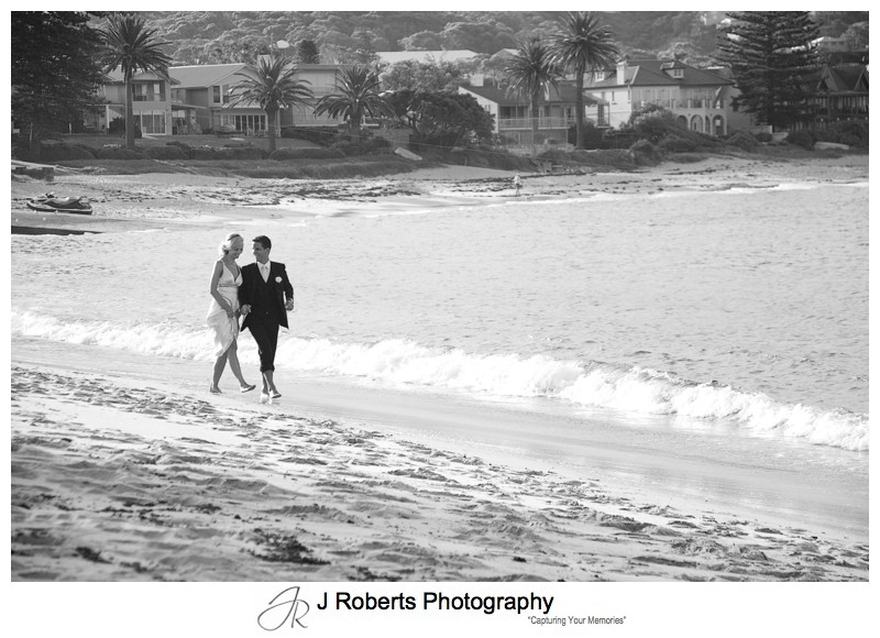 B&W of couple walking along Long Reef Beach - wedding photography sydney