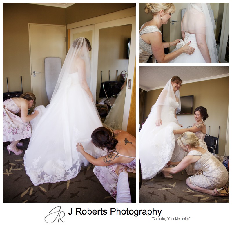 Bride getting into her dress with help from attendants - wedding photography sydney